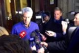 Anthony Foster speaks to several reporters on a street in Rome at night.