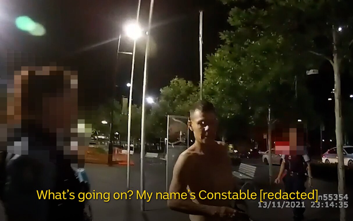 Body-worn camera footage of police stopping a shirtless man at night.