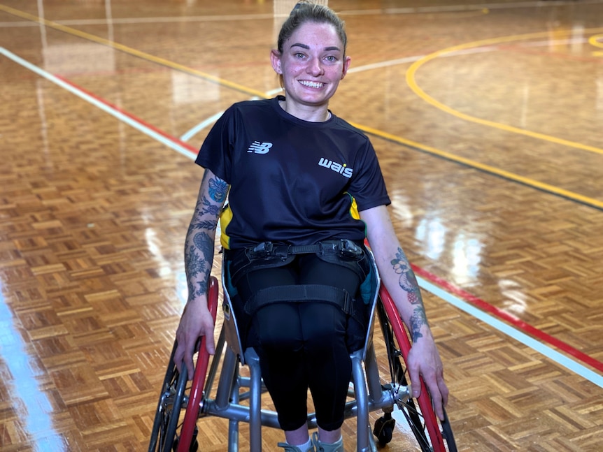 Wheelchair basketballer Taishar Ovens sits in her chair, holding the wheels and smiles at the camera
