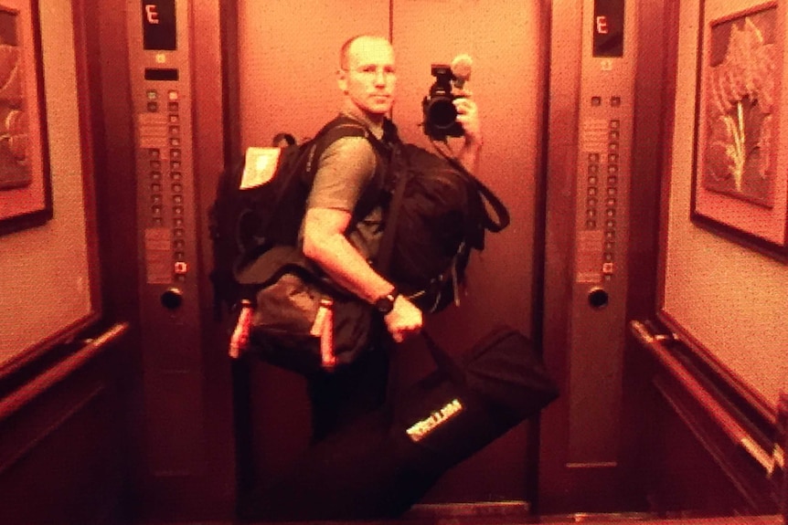 Cochrane holding camera and multiple bags.