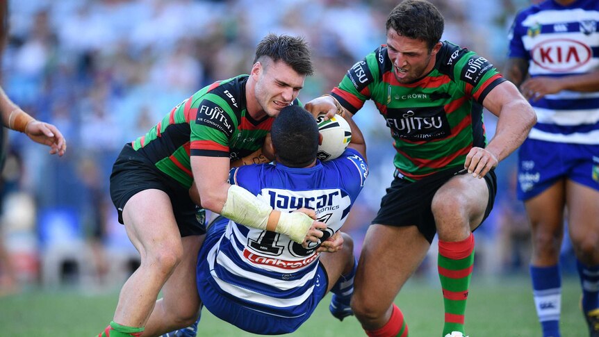 Francis Tualau of the Bulldogs is tackled by South Sydney players at Sydney's Olympic stadium.