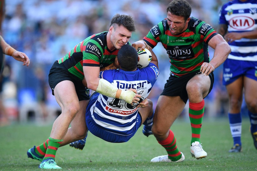 Francis Tualau of the Bulldogs is tackled by South Sydney players at Sydney's Olympic stadium.