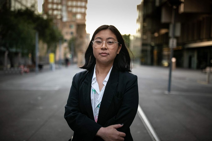 A black haired woman looks at the camera with glasses on