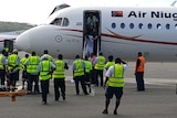 Authorities stand around a plane as a passenger is taken off