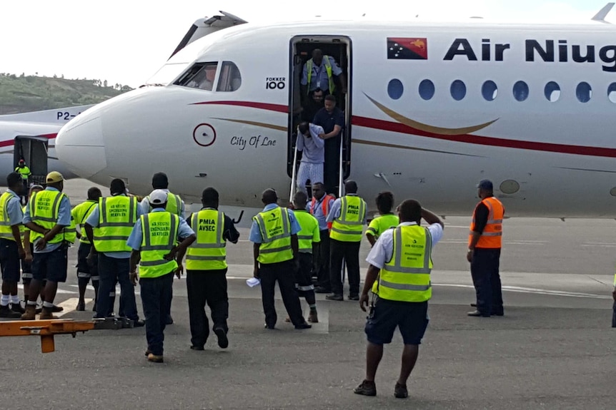 Authorities stand around a plane as a passenger is taken off