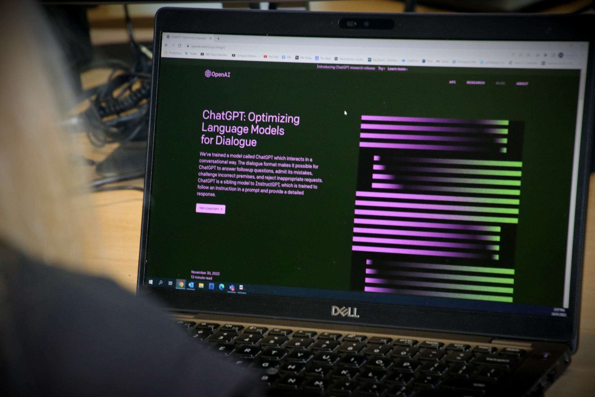 A woman sits in front of a computer open to a screen showing purple and green colours