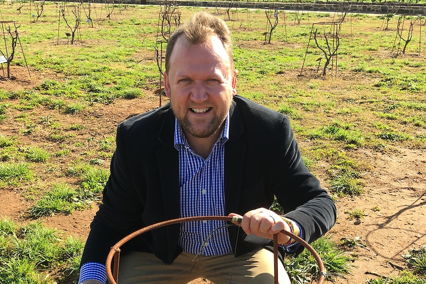 New South Wales Wine Industry Association Executive Officer Angus Barnes crouching at a vineyard