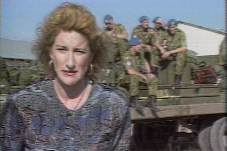 O'Neill standing in front of truck with peace keeping troops on back.
