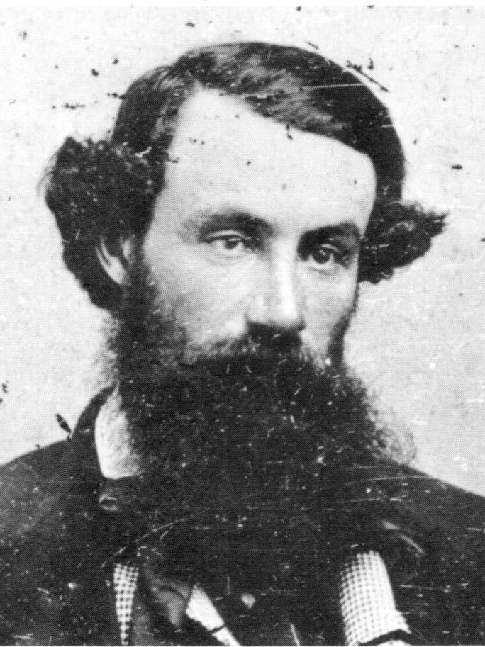 A black and white photo of a heavily-bearded man looking off-camera.