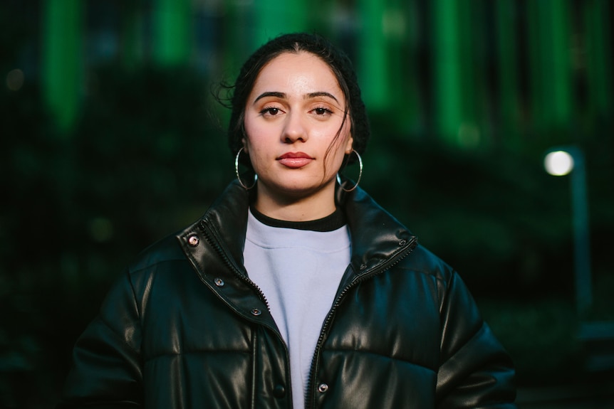 Young Muslim woman Jasmine Joyan wearing black beanie and puffer jacket at dusk.