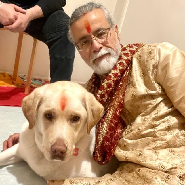 A man and a labrador pose for a photo on the floor on Diwali. 