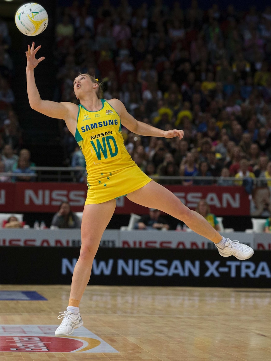 Gabi Simpson jumping in the air to catch a ball with her right hand for Australia against New Zealand.
