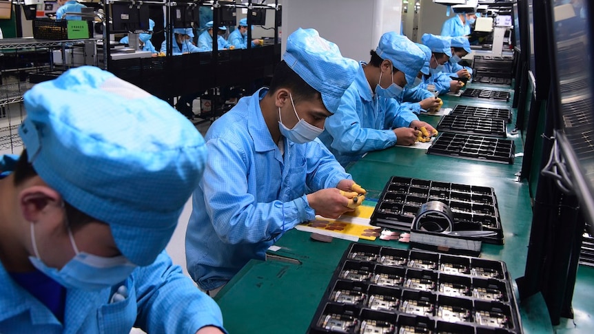 Workers wearing masks labour at a factory for Chinese telecommunications company OPPO.
