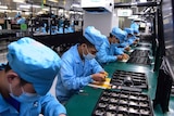 Workers wearing masks labour at a factory for Chinese telecommunications company OPPO.