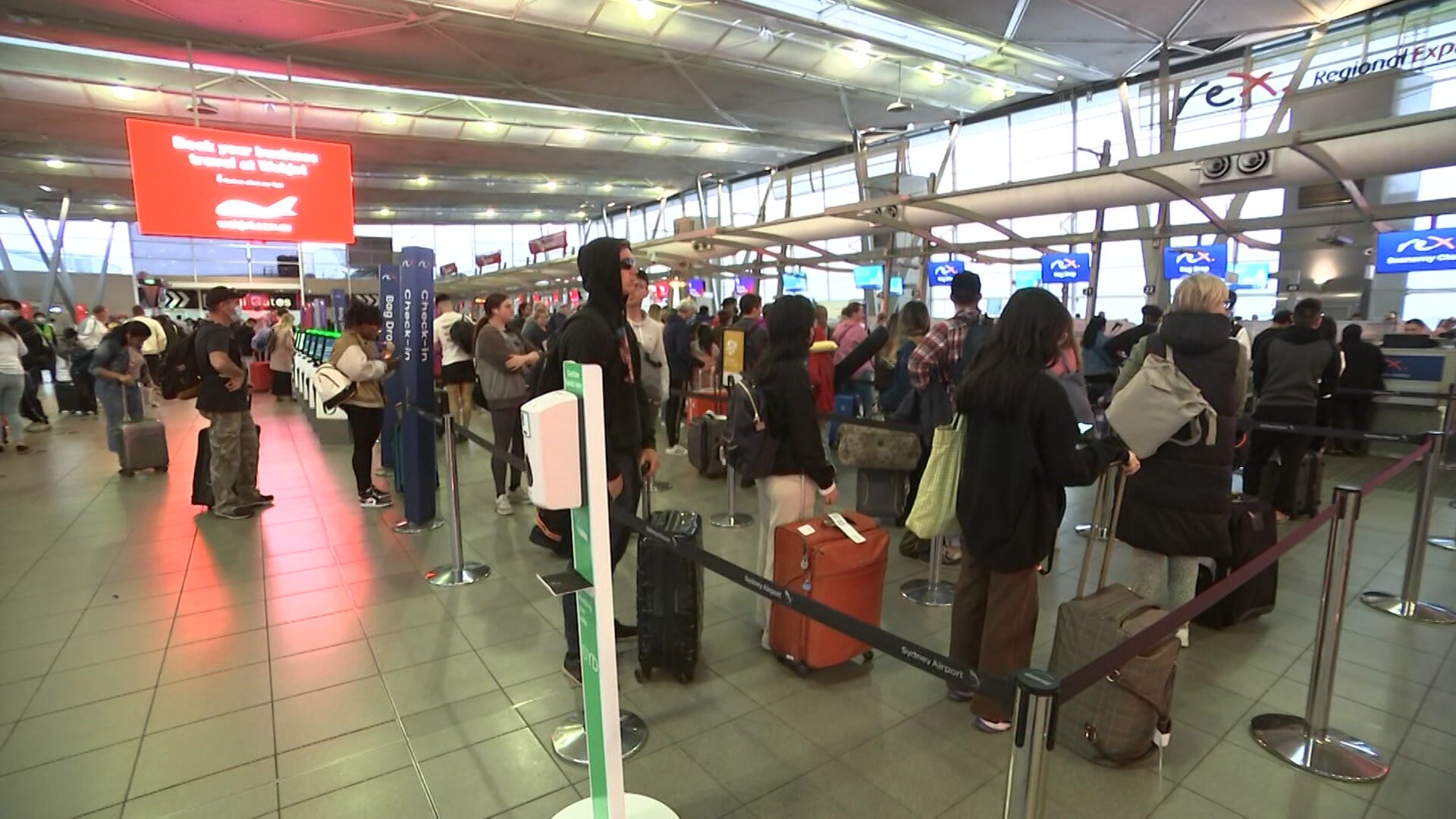 People standing in a long queue at an airport