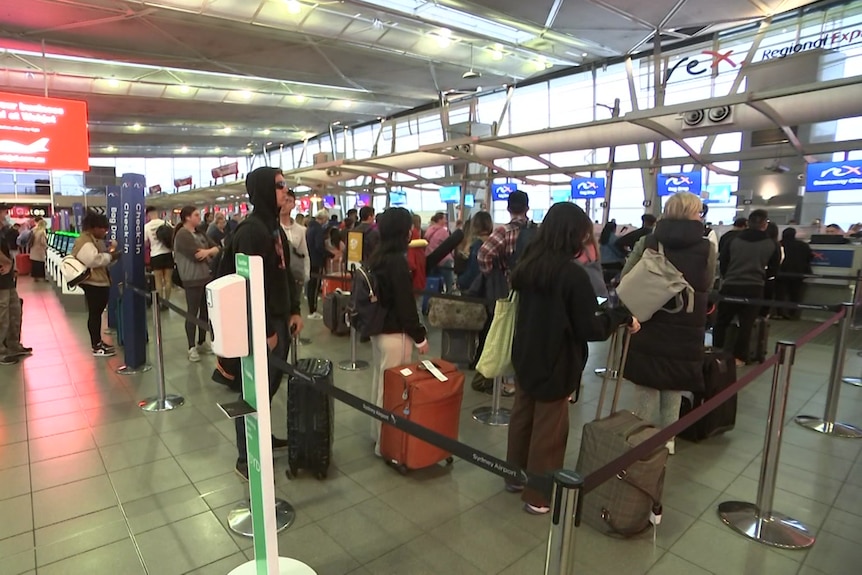 People stand in a long queue at an airport