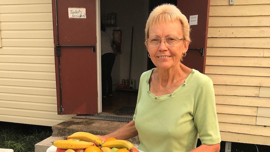 A woman holds a fruit platter in front of the open doors of the Marlee Public Hall