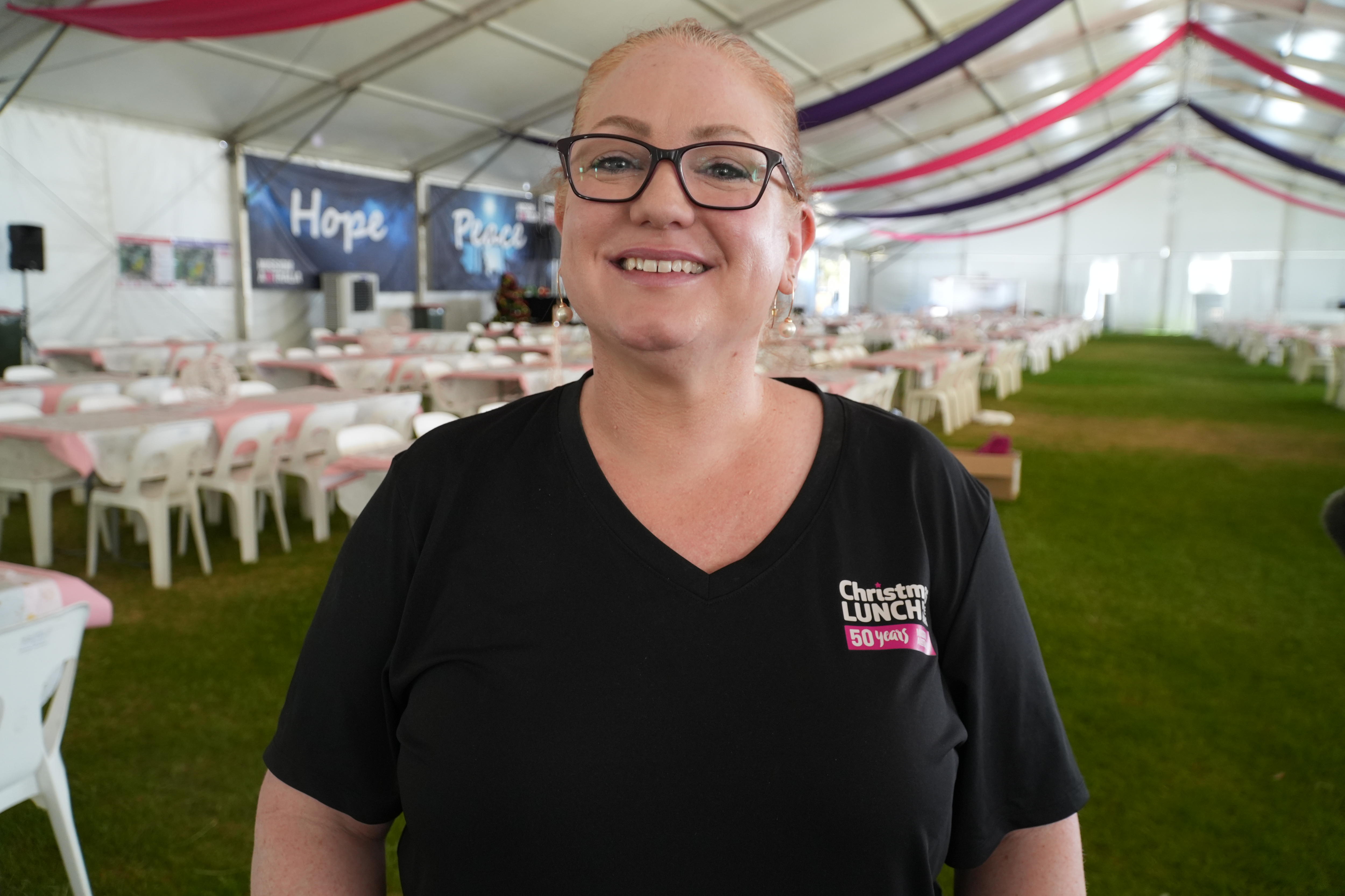 Uma mulher de óculos sorrindo para a câmera.