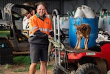 man standing behind quad bike with dog on the seat