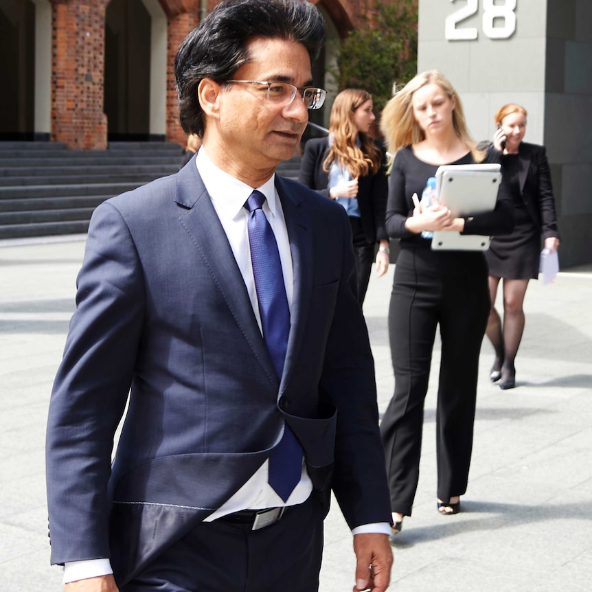 A mid shot of Lloyd Rayney walking on a footpath outside court.