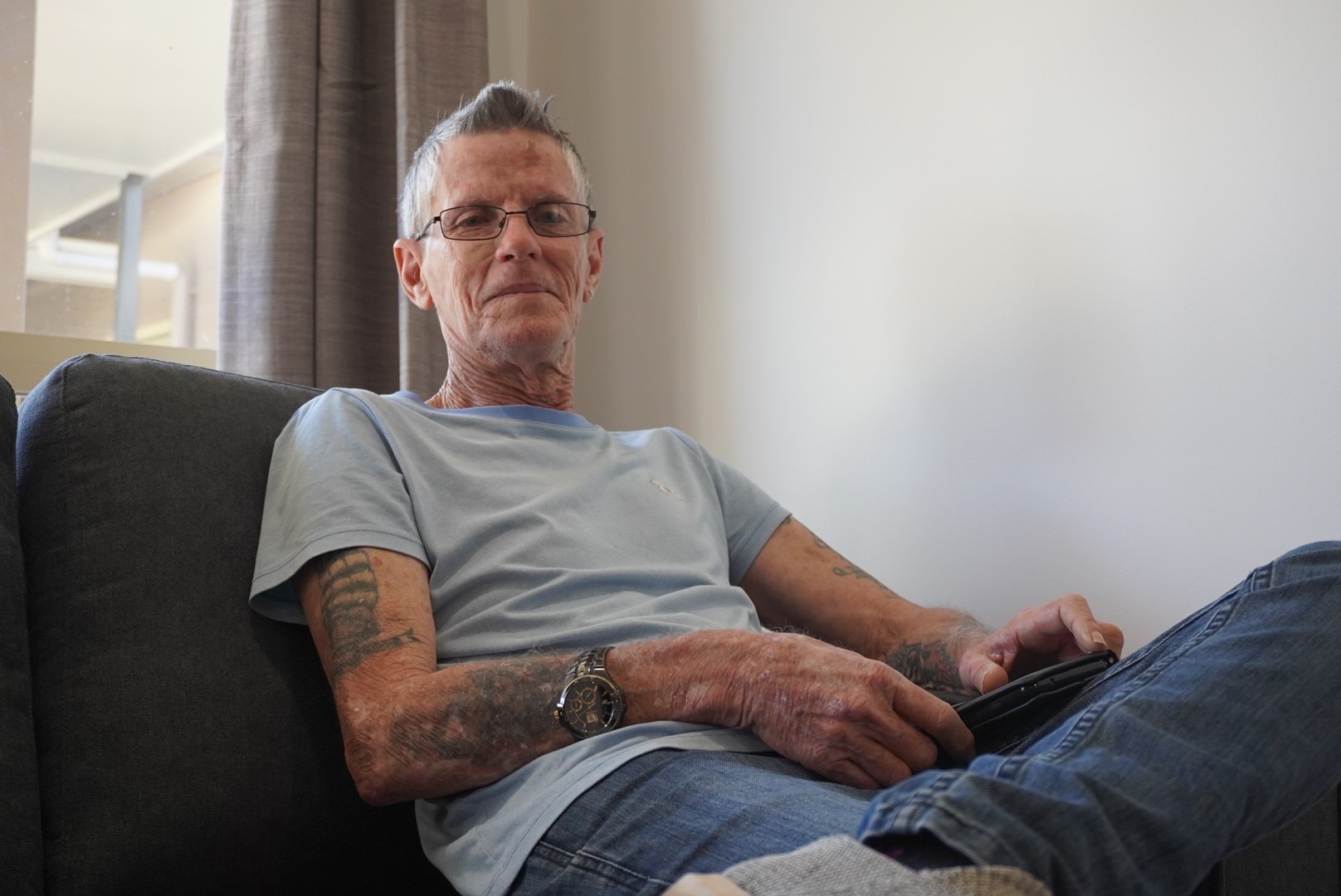 A man with a t-shirt sitting on a couch