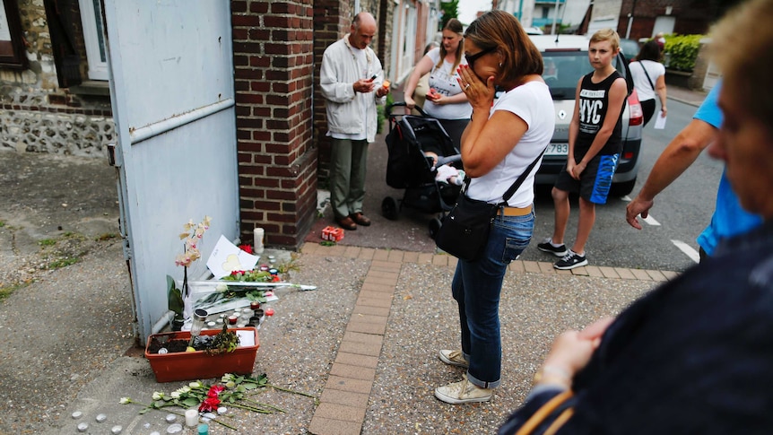 A woman prays in front of the house of Father Jacques Hamel on July 27, 2016 in Saint-Etienne-du-Rouvray