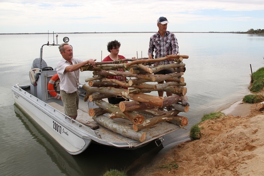 three men stand on a boat with wooden structure