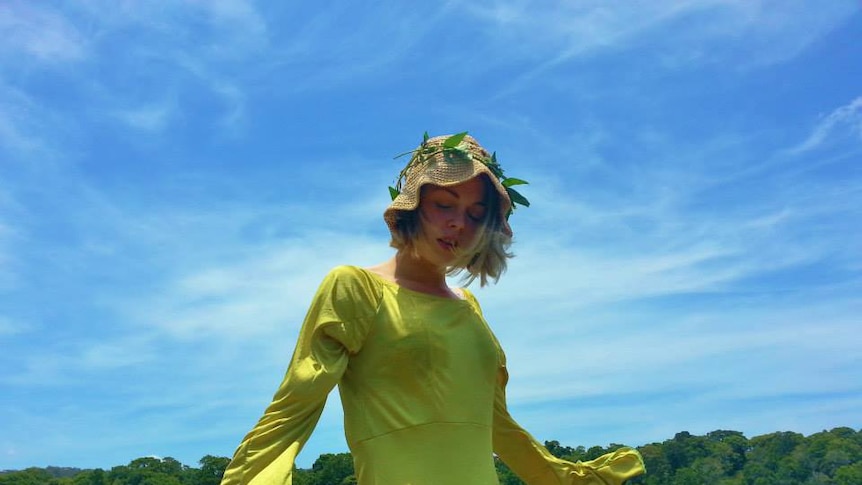 Girl in yellow dress standing in front of blue sky