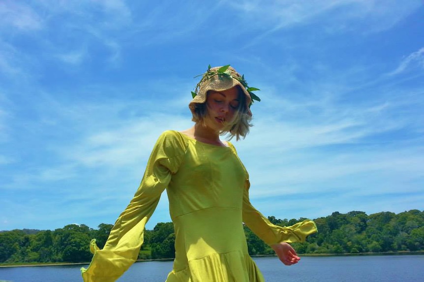 Girl in yellow dress standing in front of blue sky