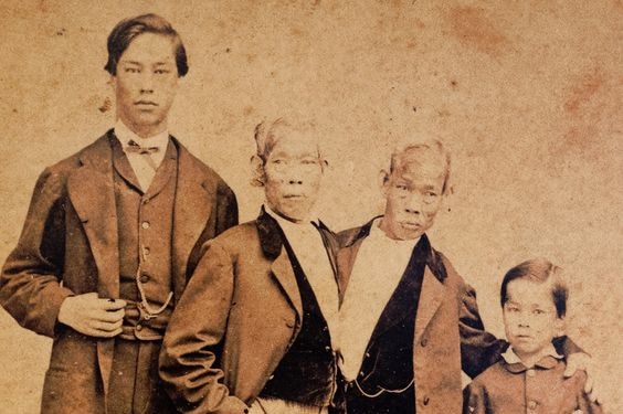Eng Bunker stands with his 15-year-old son Patrick Henry (left), and Chang Bunker with his 8-year-old son Albert (right). This photo was taken circa 1865