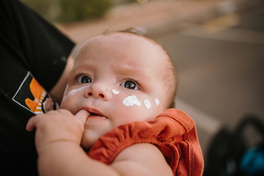 An infant with white face paint.