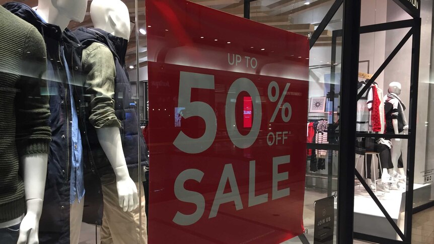 A sign saying 50 per cent off sale at a clothes shop.