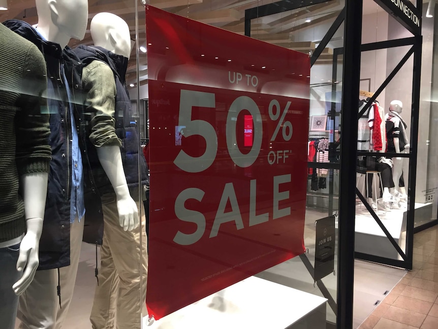 A sign saying 50 per cent off sale at a clothes shop.