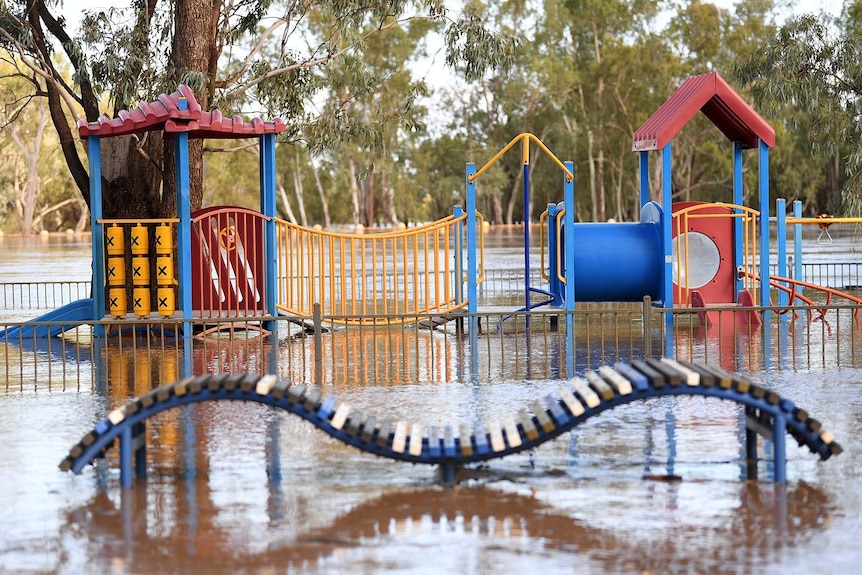 A playground inundated with floodwaters from the river behind it