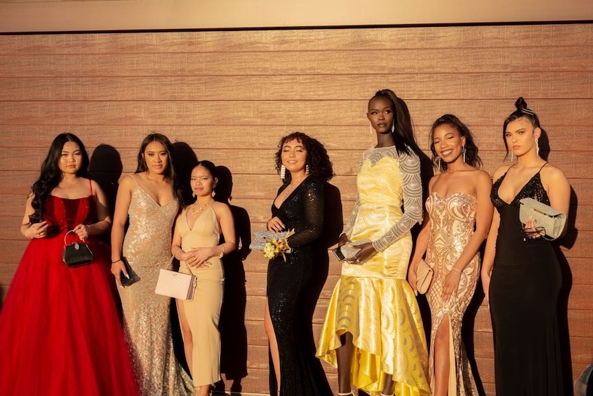 A group of young women pose in formal dresses