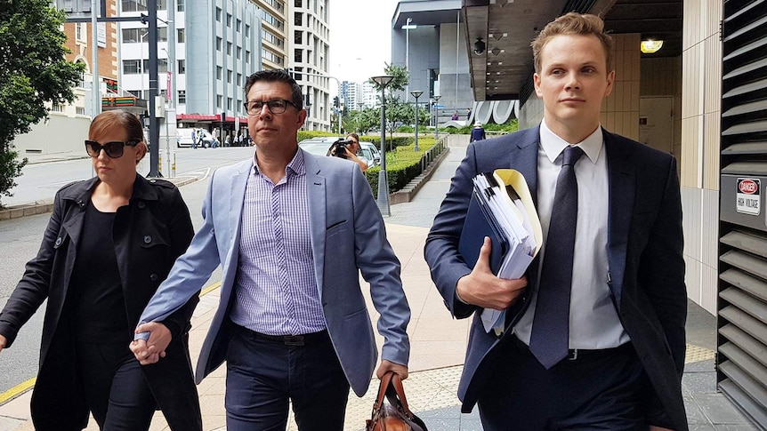 Andrew Antoniolli (centre) with his wife Karina, walk down Brisbane street with defence lawyer Dan Rogers.