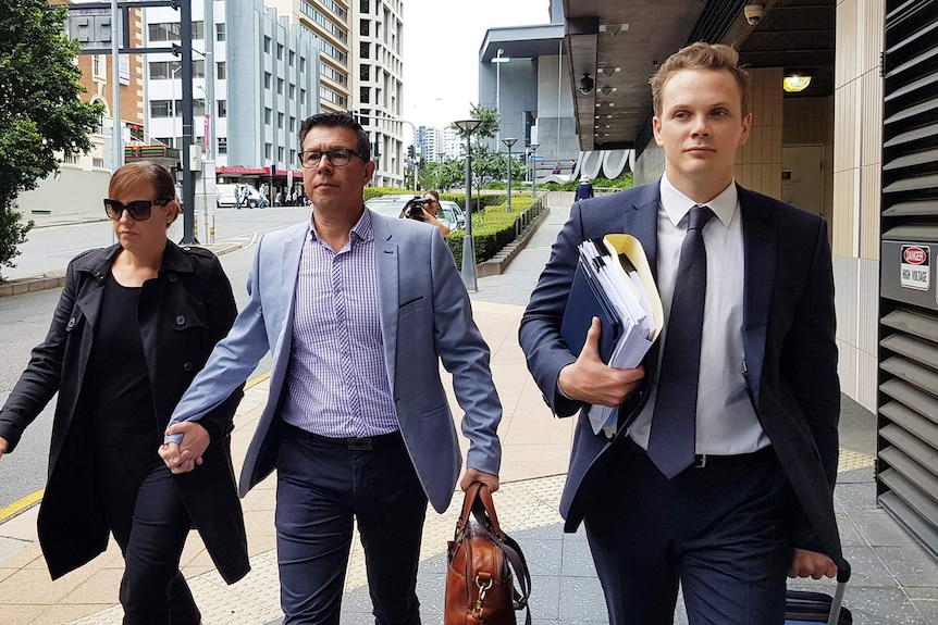 Andrew Antoniolli (centre) with his wife Karina, walk down Brisbane street with defence lawyer Dan Rogers.