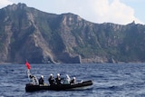 A Japan Coast Guard boat and vessel sail past one of the disputed Senkaku islands