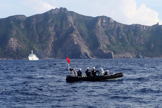 A Japan Coast Guard boat and vessel sail past one of the disputed Senkaku islands