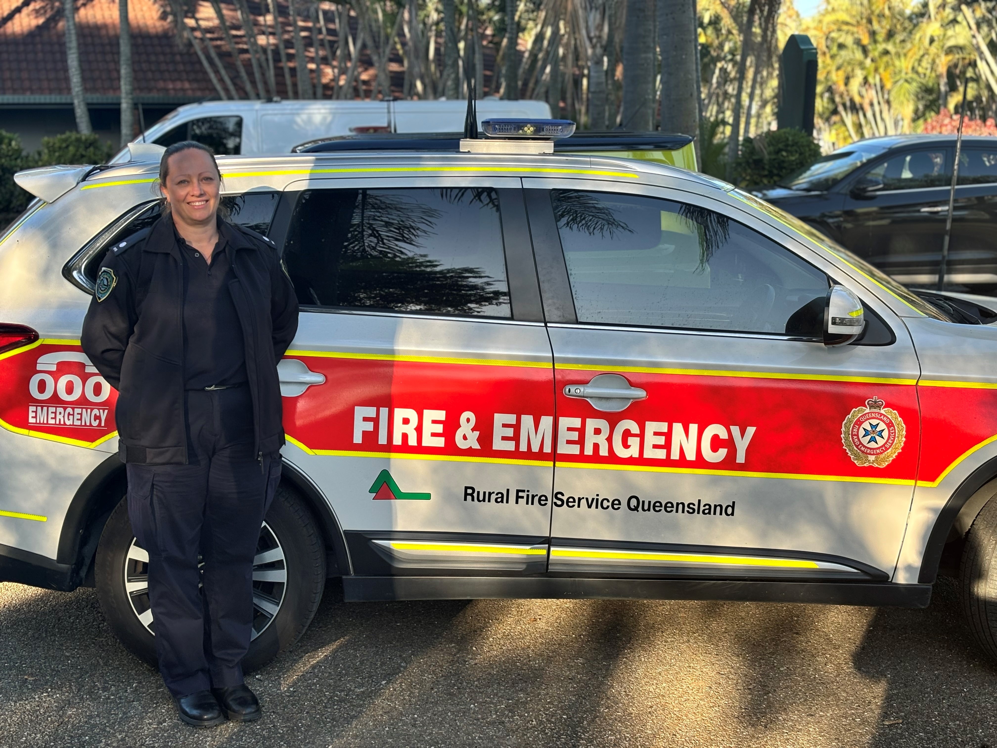 A woman standing in front of an emergency vehicle. 