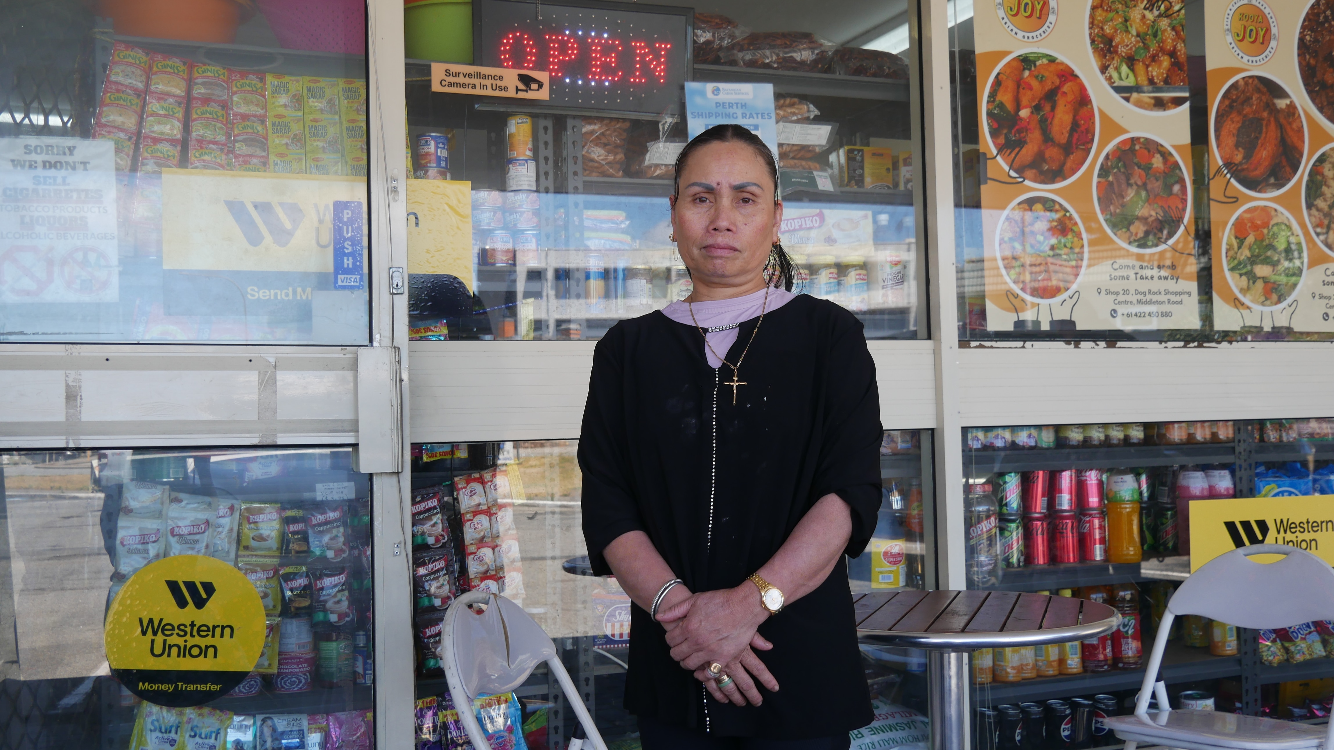A woman standing in front of a glass and windows with adverts in them