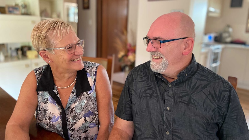 Man and women smiling at each other with kitchen in the background.