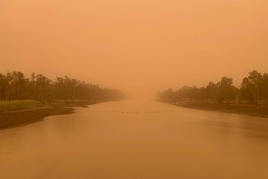 A river and sky are bathed in orange light and you can't see far into the distance