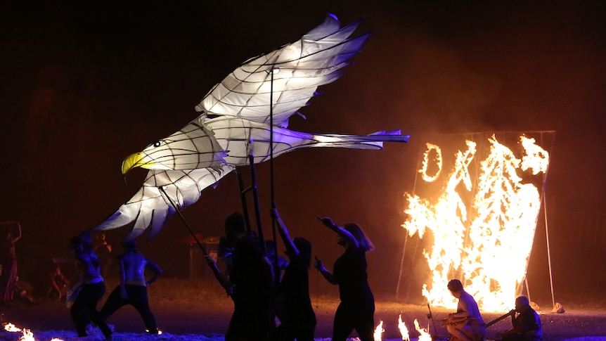 Performers dance with lit up paper seagull puppet.
