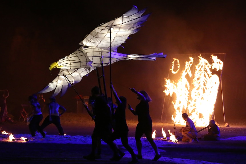 Performers dance with lit up paper seagull puppet.