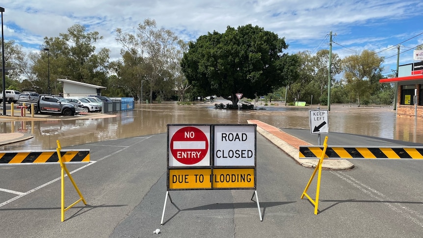 A flooded road with signs indicating its closure.