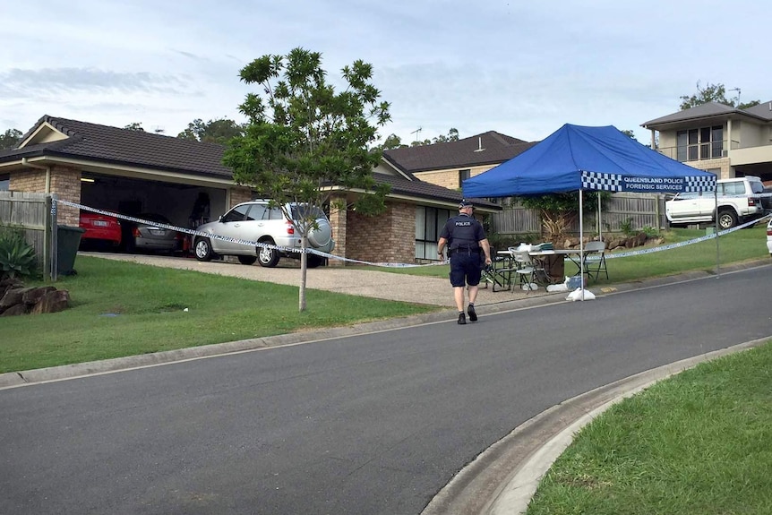 A police officer walks towards the cordoned-off house on Skylark Street in Upper Coomera