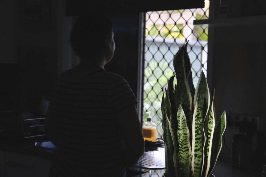 Silhouette photo of 'Jane' from Brisbane looking out the window in her kitchen, unidentified.