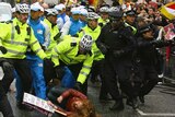 A protester is knocked to the ground by police surrounding the bearer of the Olympic Torch