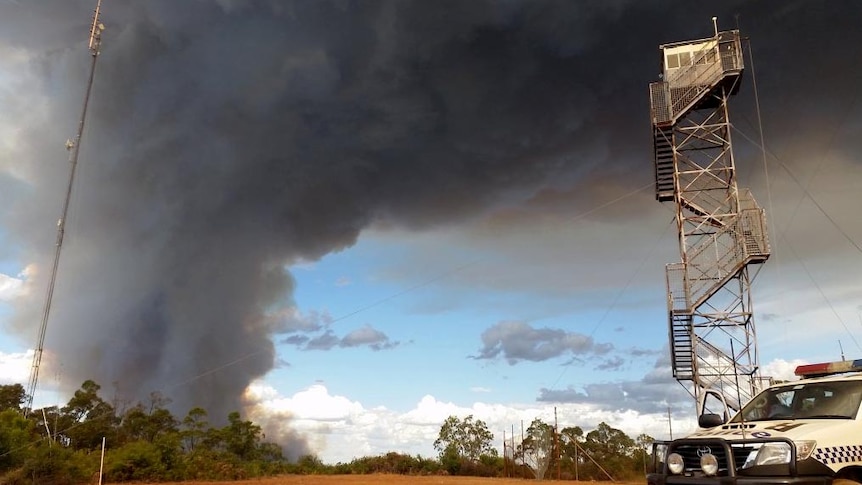 Smoke from the Waroona bushfire rises above a police vehicle and observation tower.